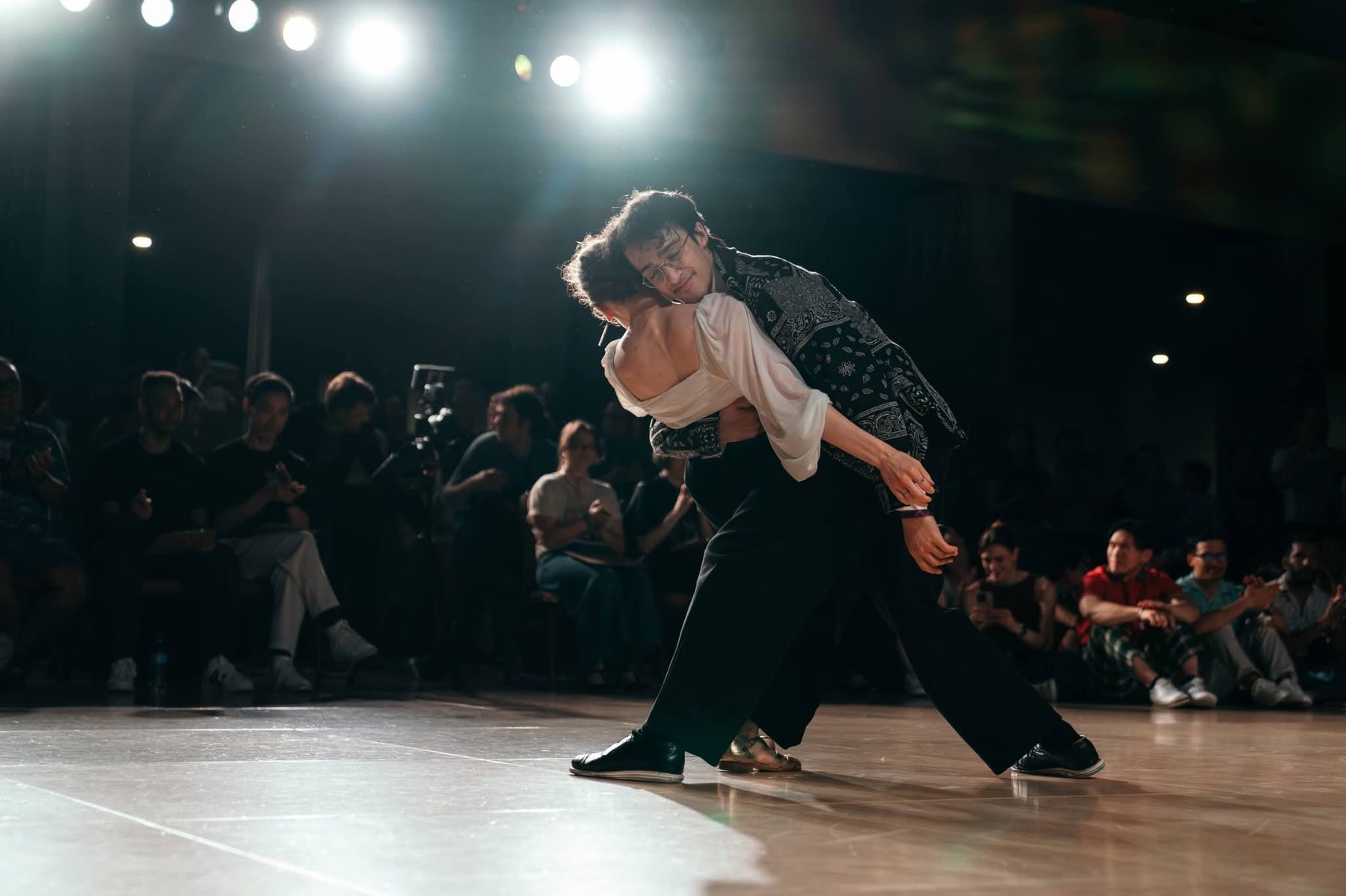 Grace and her partner mid-dip on a competition floor, ringed by a watching crowd.