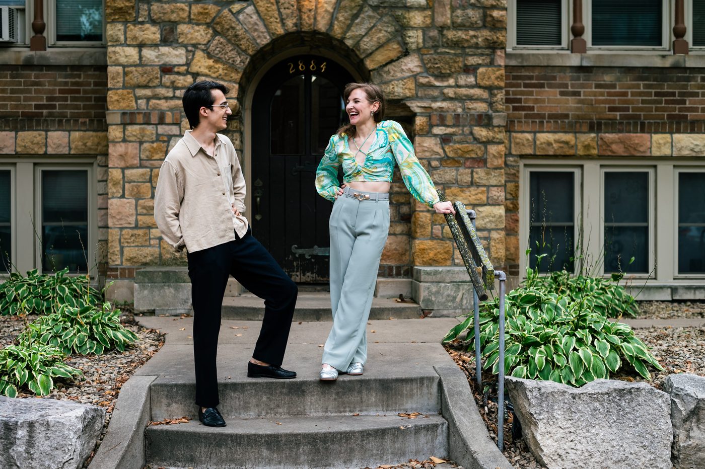 Grace and her dance partner laughing on the front steps of a stone apartment building.